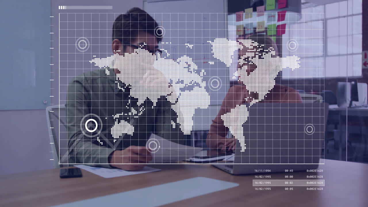 World map animation over two people discussing at office desk with laptop