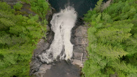 Aerial-Rising-Shot-Above-Big-Waterfall-and-Tall-Spruce-Trees
