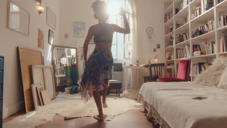 black girl in headphones dancing barefoot in sunlit room