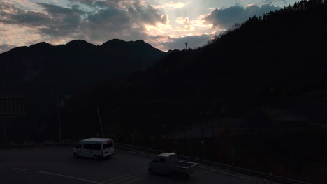 Vehicles-driving-on-a-rural-road-in-the-mountains-in-the-evening