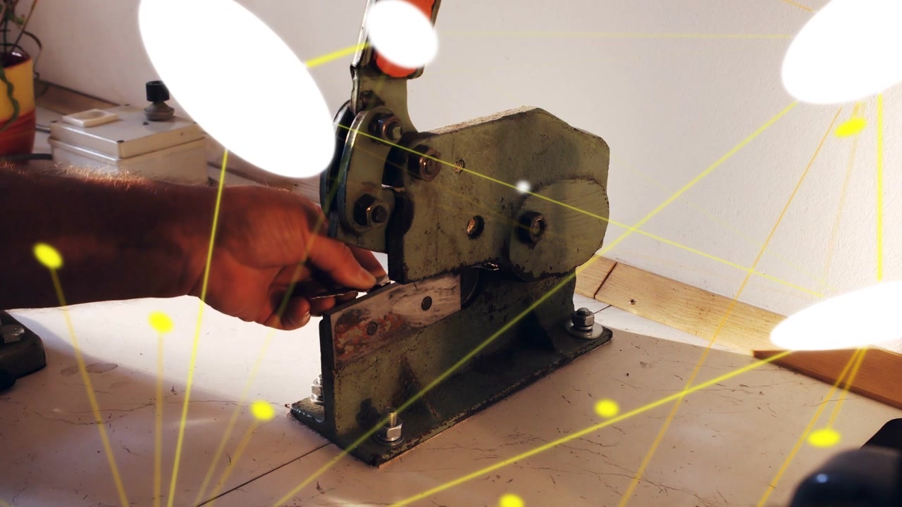 Tecnico che tira una leva arancione tranciando un pezzo con delle cesoie, con sovrapposizioni bianco-gialle che nascondono la vista per la lavorazione dei metalli.