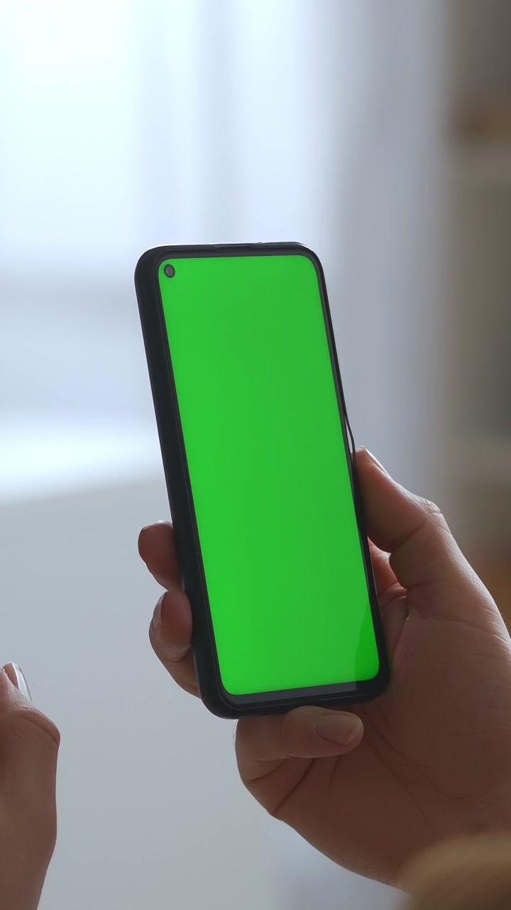 Primo piano di mano che regge uno smartphone verticale con schermo verde