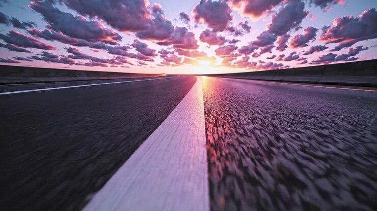 Dramatic low-angle shot of a road at sunset, with vibrant clouds