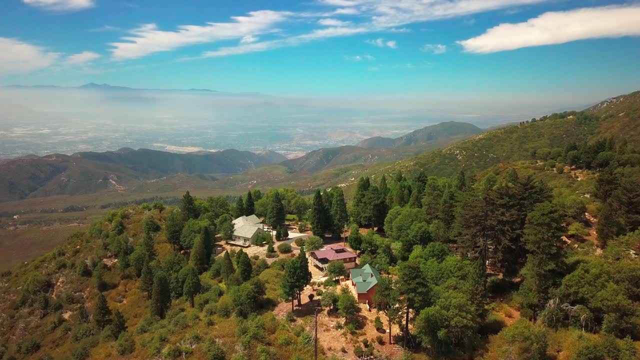 Aerial flyover high-altitude ridge with foliage to reveal a vast desert valley below. 4K