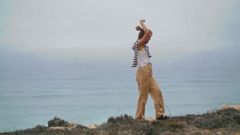 Relaxed-woman-walking-ocean-cliff-edge.-Carefree-person-stretching-enjoying-sea