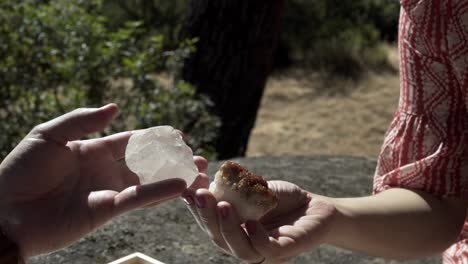 man is looking at a rock that looks like white crystals, while a girl is looking at another rock that has brown silt features that are dazzling and sparkly