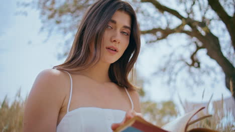 modelo morena leyendo libro prado retrato de la naturaleza. mujer joven mirando cámara