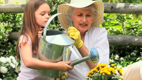 una niña con su abuela regando una planta