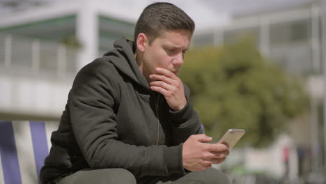 hombre pensativo usando teléfono celular al aire libre