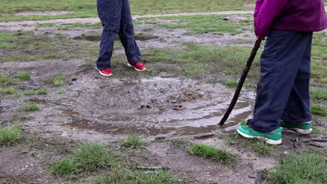 dos niños étnicamente diversos jugando con palos en un charco fangoso