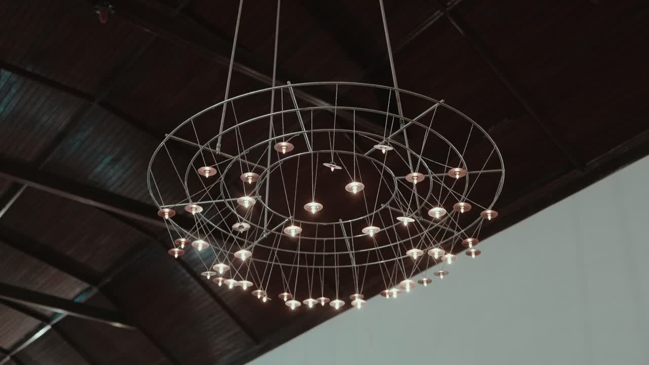 modern geometric chandelier glows under dark wooden ceiling