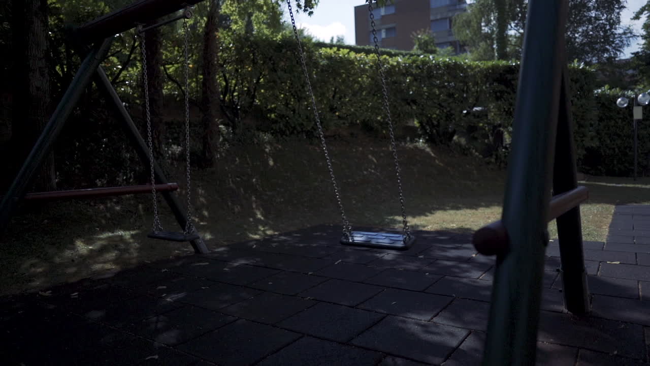 해가 지는 초록색 나무로 둘러싸인 현대 놀이터 공원에서 느린 속도로 빈 스