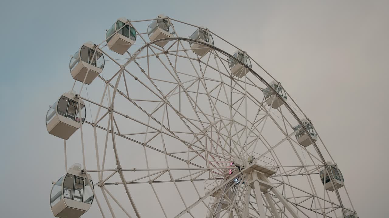 Ferris wheel with empty cabins against a cloudy sky, evoking serenity and nostalgia