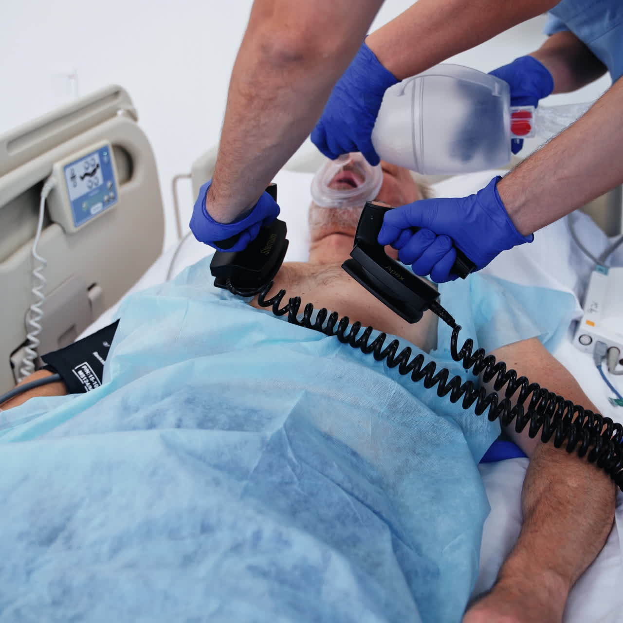 Defibrillation.Doctors save patient's life in clinic. Nurse and a specialist give resuscitation to a male patient in the emergency room. Cardiac massage.