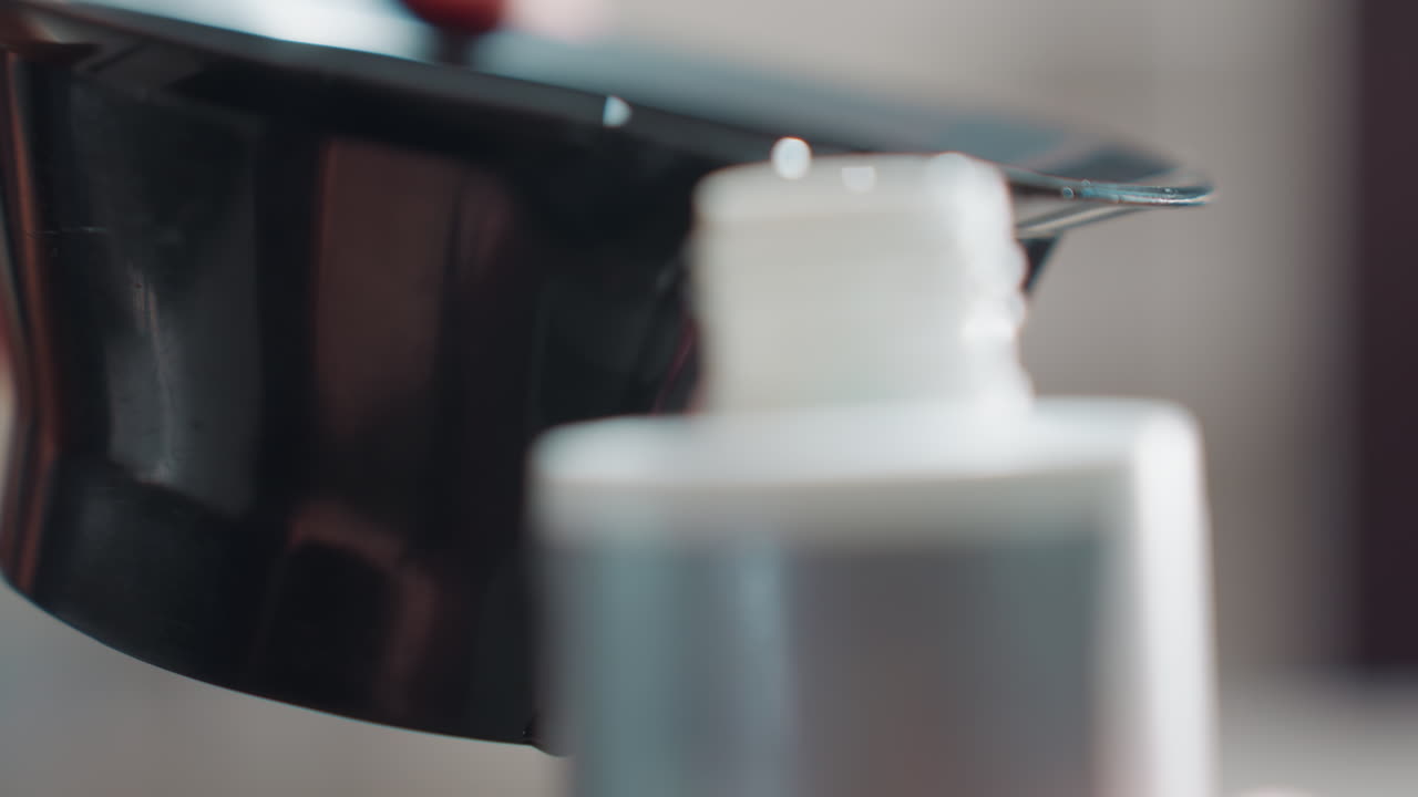 작은 용기에 조심스럽게 붓고, 정확하고 조명이 잘 갖춰진 액체 옮기기 과정을 실행하며, 올바른 조명 아래에서 그릇에서 가느다란 목이 있는 용기로 꼼꼼하게 붓는 모습