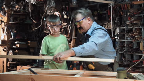 grandfather teaching grandson woodworking in a workshop