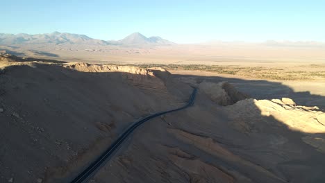 Drone-gracefully-soars-over-the-arid-landscape,of-Volcan-Licancabur,-revealing-the-highway-in-Atacama