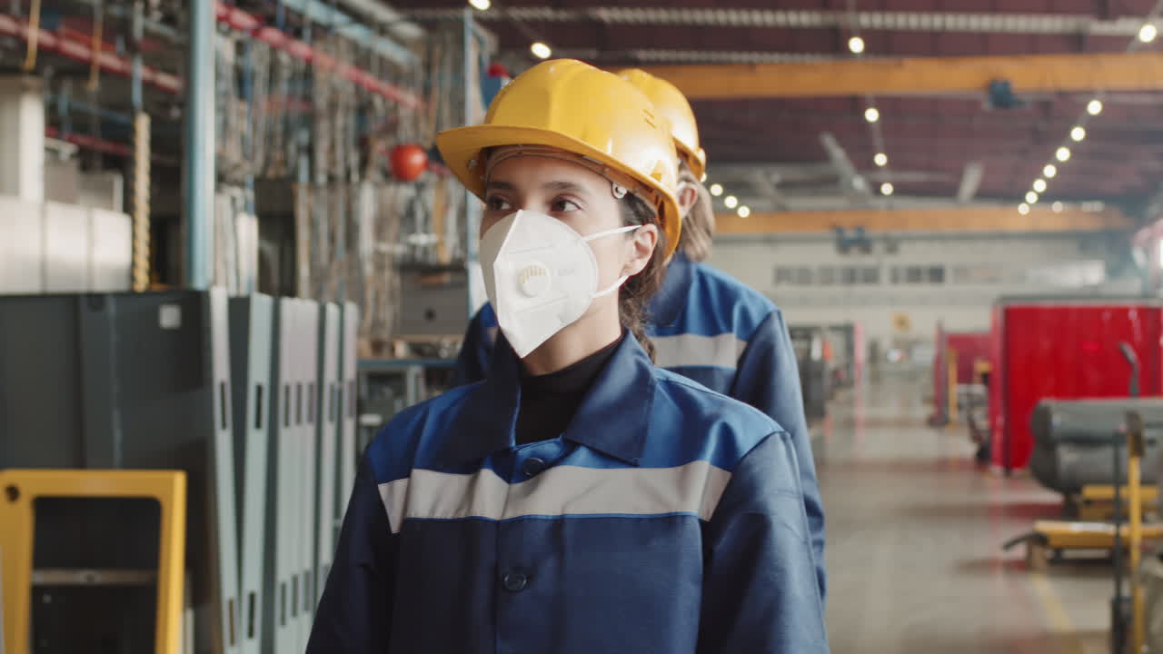 Female Supervisor With Workmen In Face Masks Walking Through Factory
