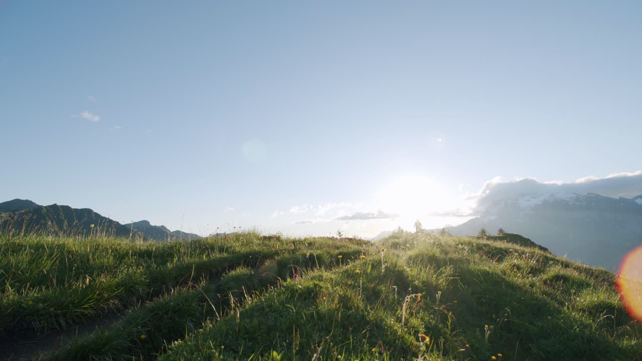 산악 자전거 타는 사람이 풀이 무성한 능선을 한 방향으로 질주한 다음 다른 방향으로 질주합니다.