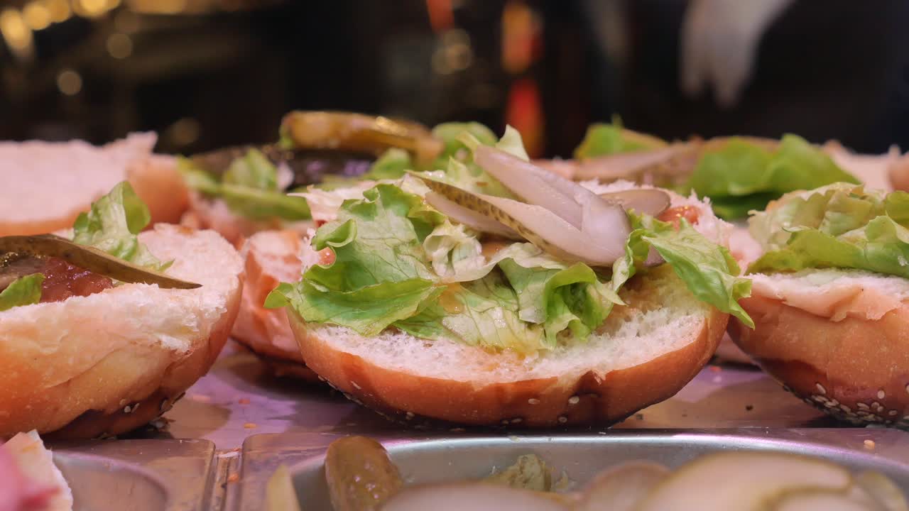 Close-up shot of a burger with lettuce, pickles and sesame seeds