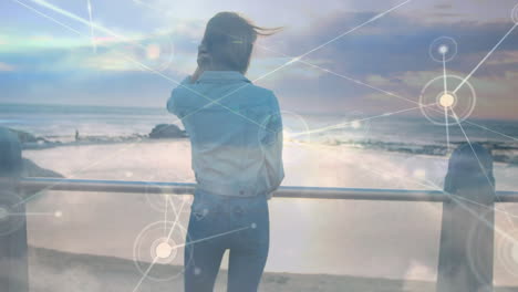 standing by ocean, woman with digital network animation overlaying scene