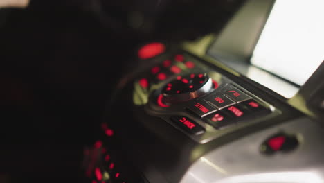 first-person view of a woman's hand pressing the tel button on a car control panel at night. the dashboard is illuminated with red lights, highlighting the controls. shot with a handheld camera