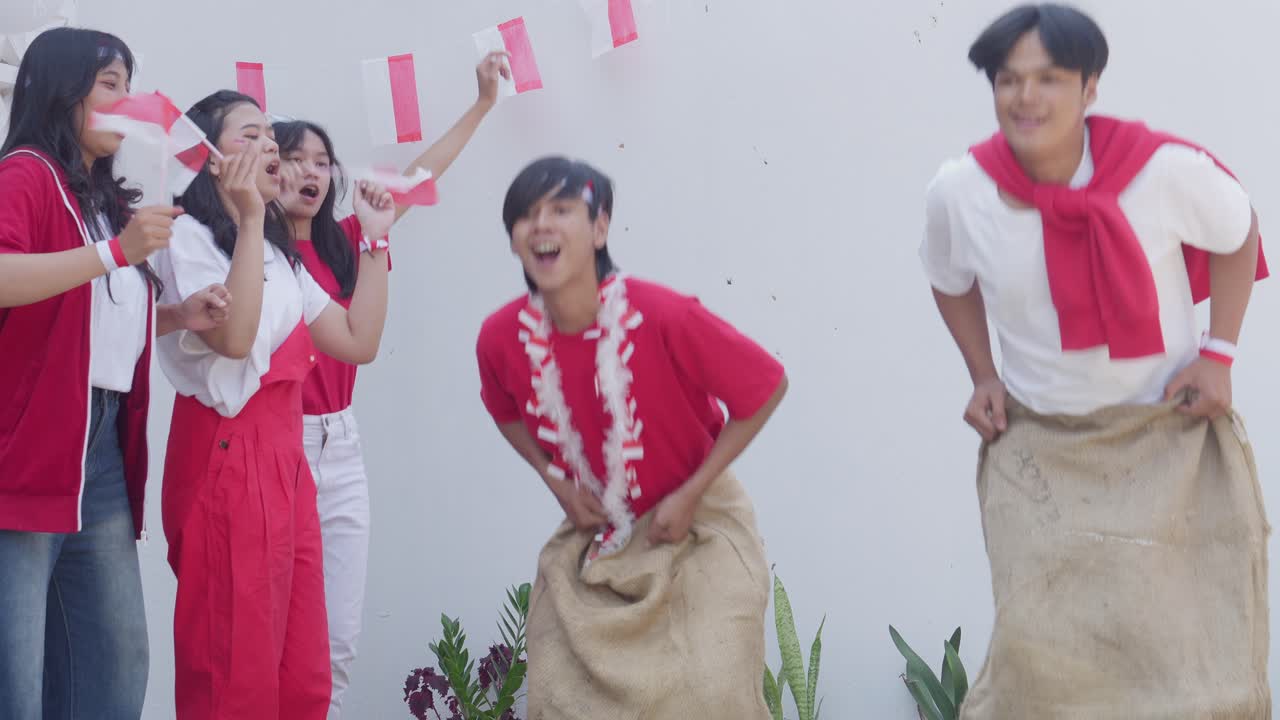 Two Asian Young Men Participate In Sack Race Called Balap Karung To Celebrate Indonesian Independence Day, August 17th.