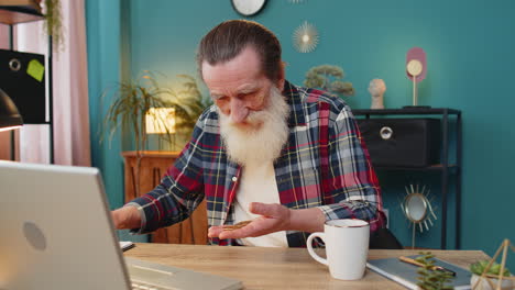 surprise senior mature man examining golden bitcoins btc with magnifying glass sitting at table