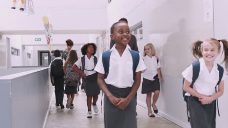 teacher and pupils walking along corridor in busy elementary school corridor