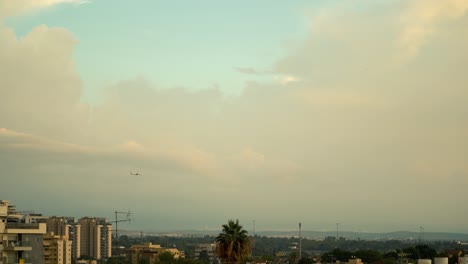 Una-Toma-De-Un-Avión-Volando-Al-Atardecer,-Fue-Tomada-Desde-El-Techo,-Israel-Tel-Aviv,-Medio-Oriente,-Coloridas-Nubes-De-Surf,-Hora-Dorada,-Paisaje-Urbano,-Video-Sony-4k