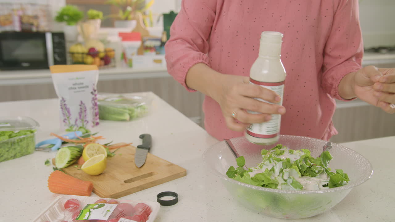 Mid Shot Of Woman Pouring Dressing On Top Of Her Salad