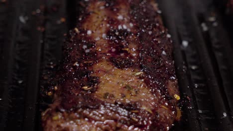 Sea-salt-sprinkling-on-cooked-beef-steak-in-cast-iron-grill,-Closeup