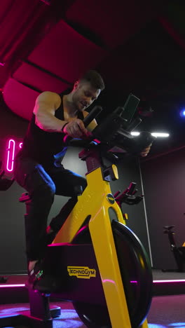 sport man exercising in fitness club. hard working young athlete trains on spinning exercise bike