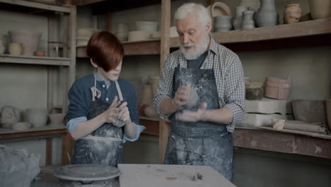 young student learning pottery from an elderly artisan