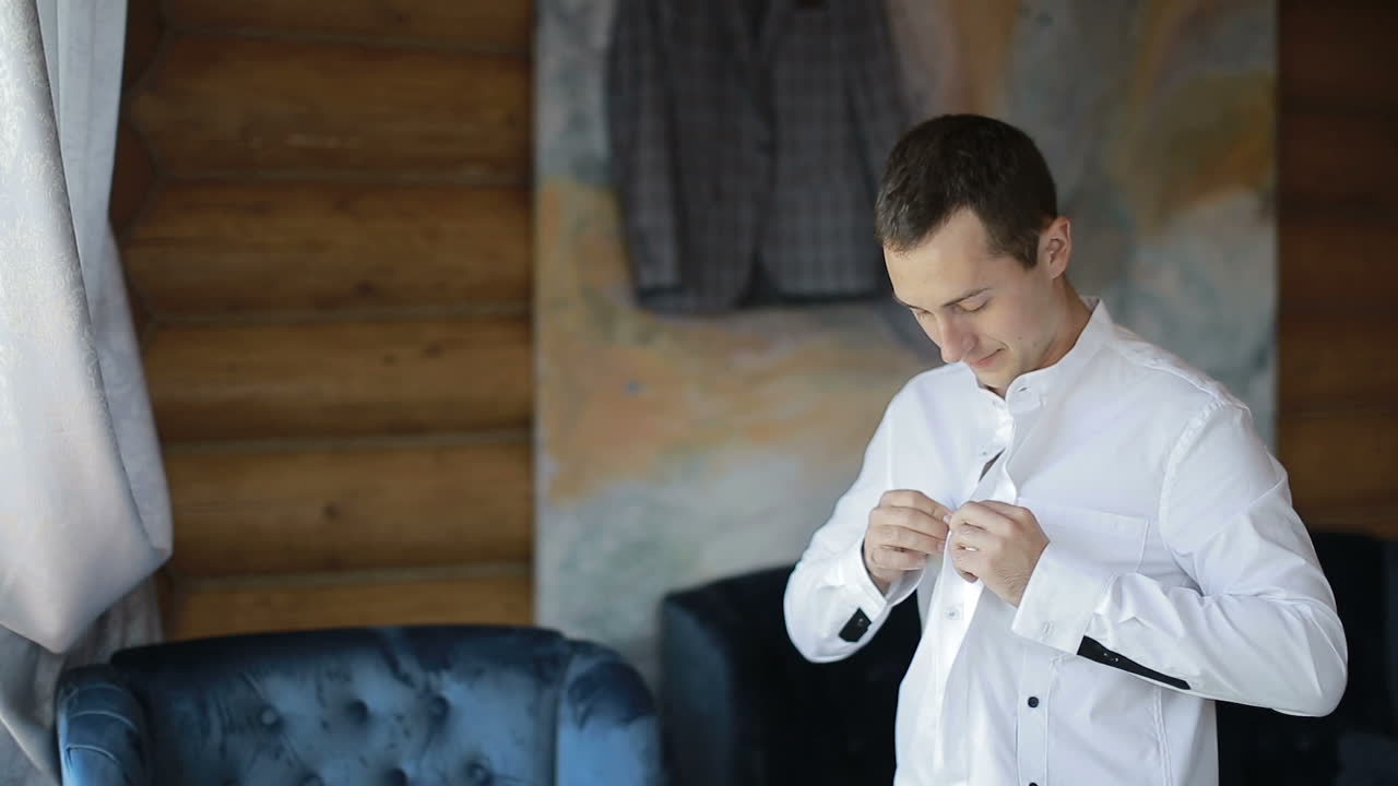 Un uomo indossa una camicia bianca. Bello sposo che si veste e si prepara per il matrimonio