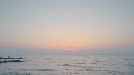 sunset over the ocean with people on the pier