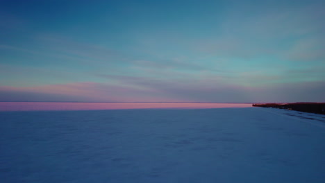 drone volando sobre un lago congelado en canadá en la hora dorada