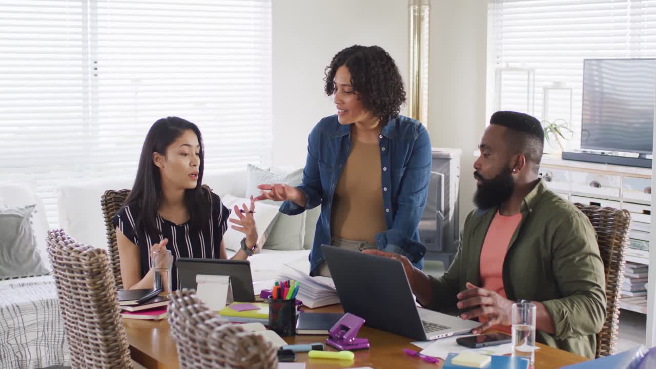 Diverse male and female friends using laptop and talking, working at home, in slow motion