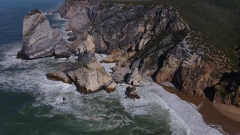 Amazing-aerial-view-of-the-colourful-rocks-and-cliff-of-Ursa-beach,-Portugal