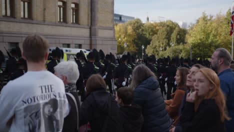 people watching royal guard parade on karl johan in oslo in front of the storting