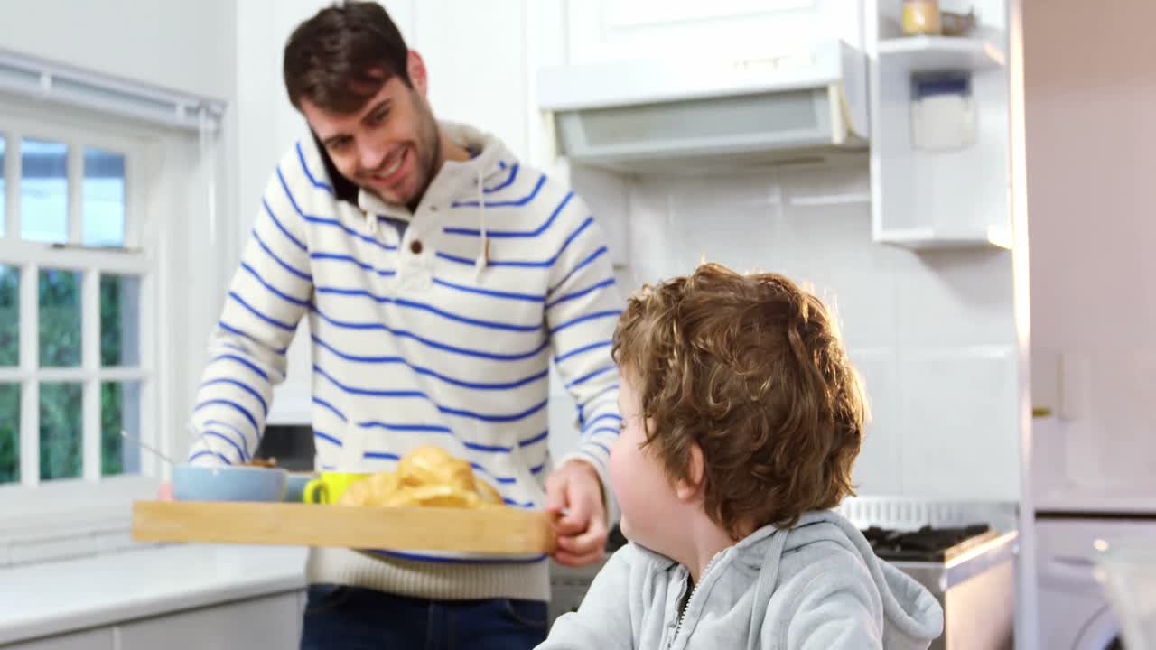 padre hablando en el teléfono móvil mientras el hijo usa la tableta digital