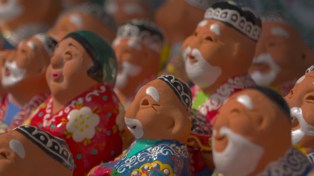 特寫色彩繽紛的手工黏土公仔，帶著笑臉和傳統服飾，在紀念品攤位展示。明亮的民間工藝細節、淺景深和文化主題。