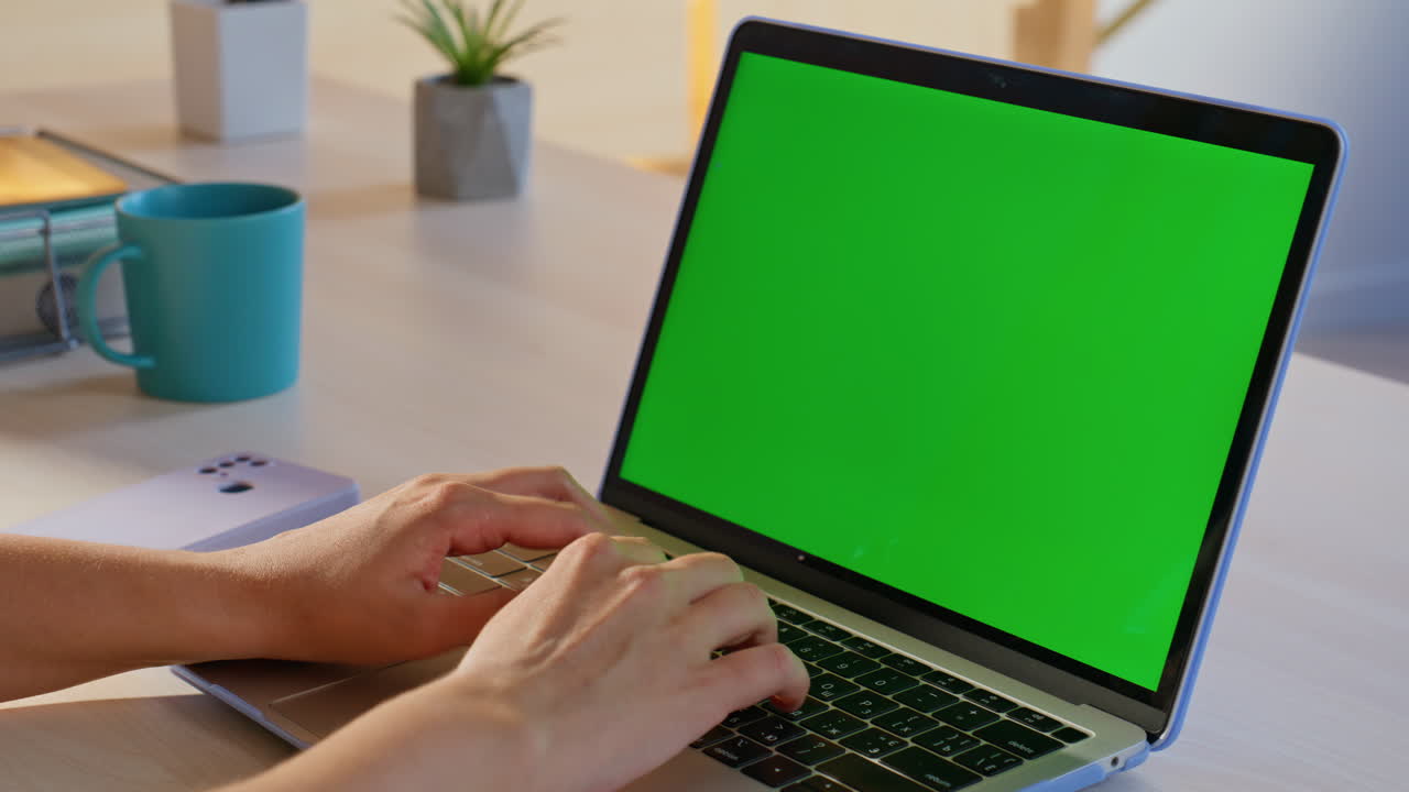 Typing on a laptop with a green screen