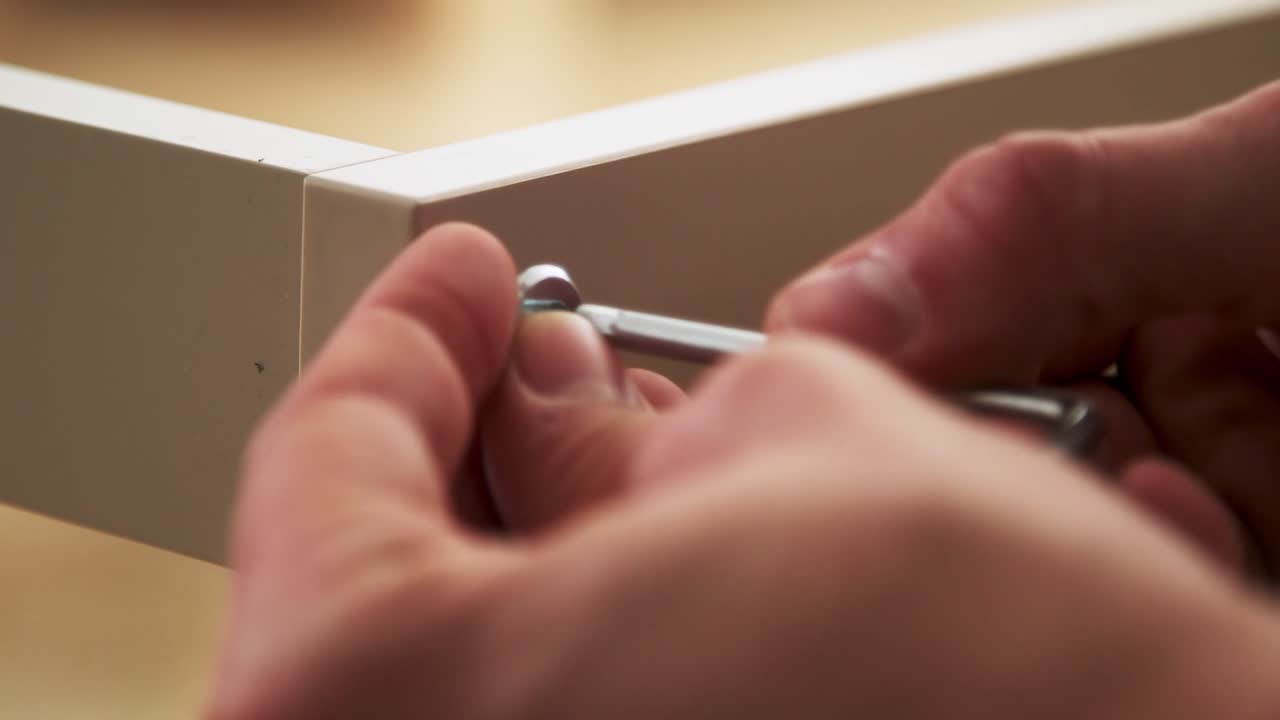 manos caucásicas atornillan un tornillo con cabeza allen en un zócalo