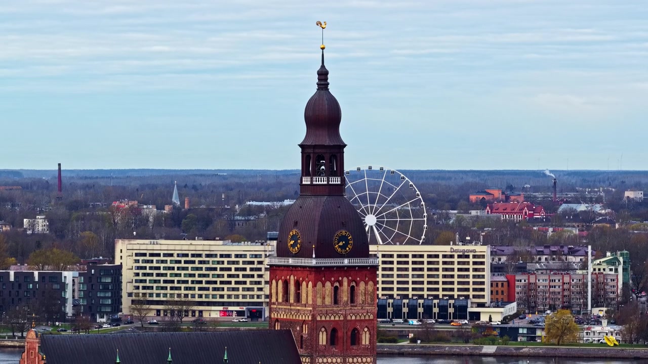 Stort historiskt klocktorn med ett pariserhjul som snurrar i stadsbilden, dagsvy