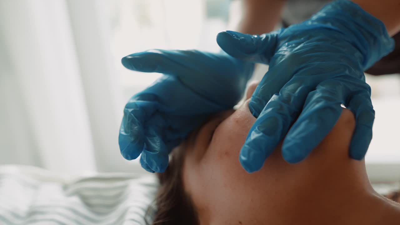 Primo piano di mani guantate che eseguono un trattamento di bellezza per il viso