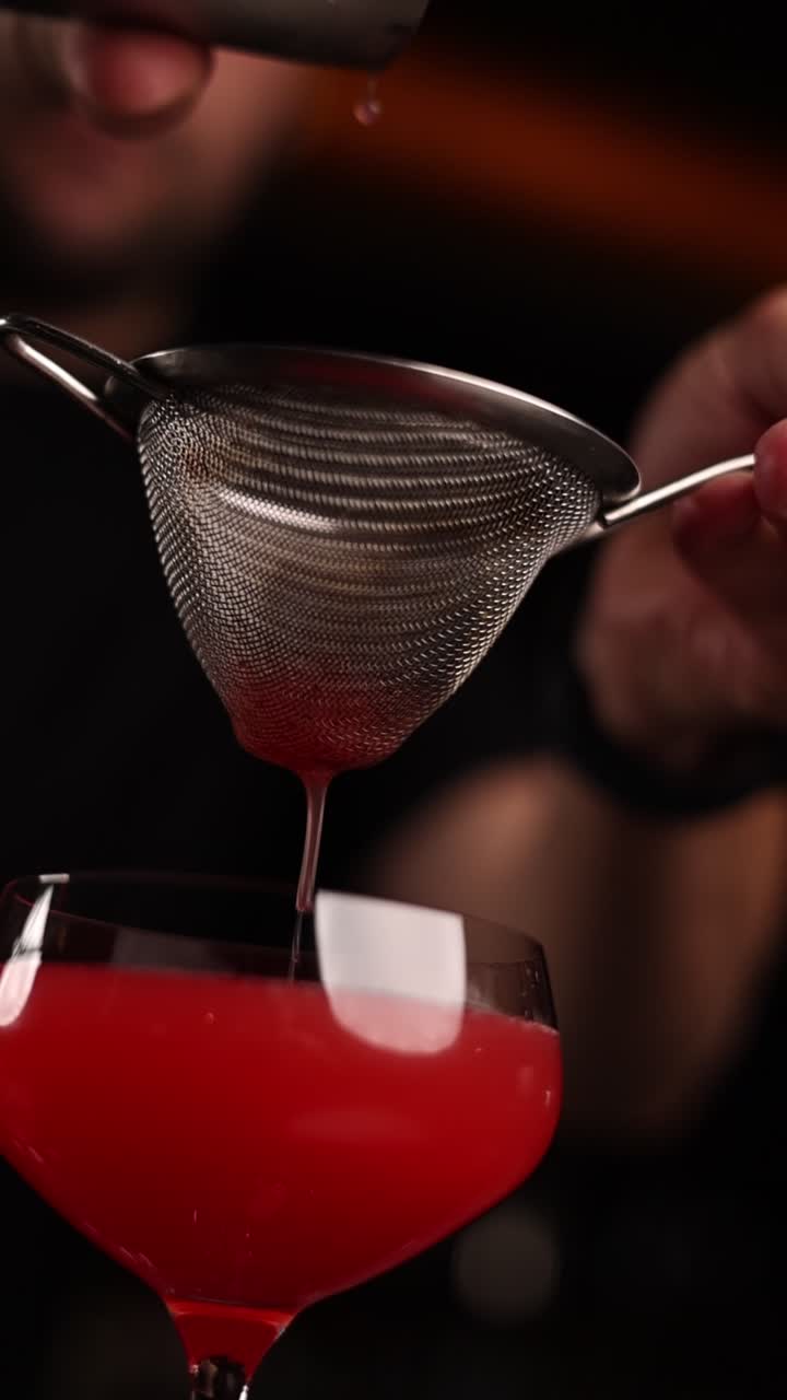 Bartender tilbereder en rød cocktail