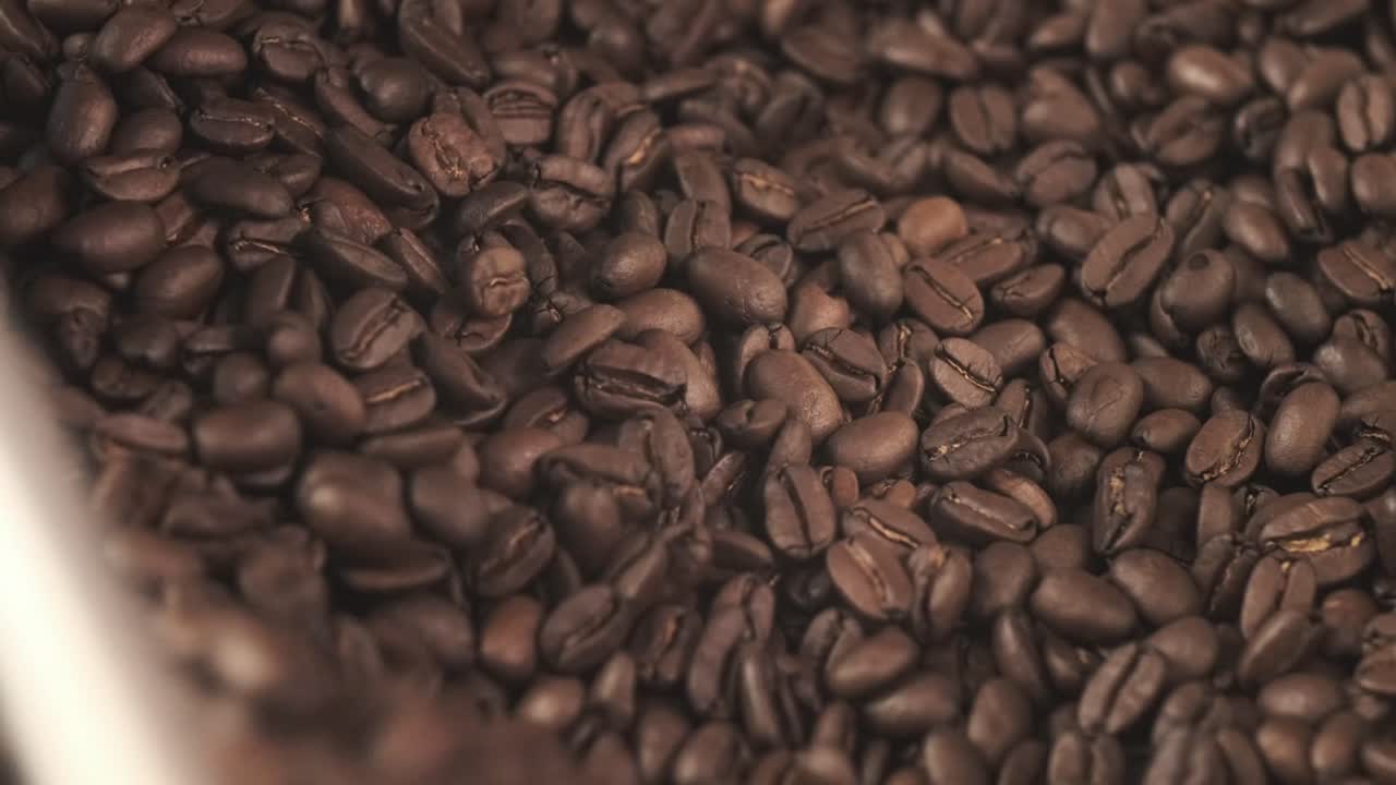 Chicchi di caffè tostati che ruotano all'interno di una miscelatrice, sprigionando aroma e un ricco color marrone