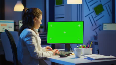 Woman-looking-at-computer-with-chroma-key-during-night-time
