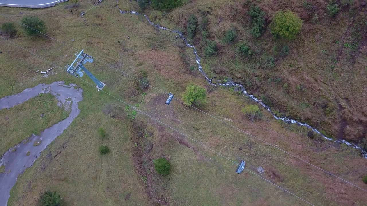 이탈리아 북부의 백운석 산을 오르는 스키 리프트 곤돌라의 공중 최고 전망, 도로 위를 지나가는 자동차, 왼쪽 팬 샷을 추적하는 드론